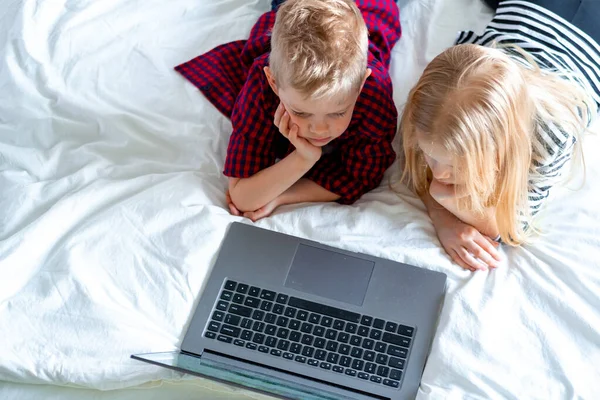 Kształcenie online na odległość. widok z góry na Schoolboy i dziewczyna studiuje w domu z notebooka tabletu cyfrowego i odrabianie zadań domowych w szkole. Siedzenie na łóżku z książkami treningowymi. — Zdjęcie stockowe