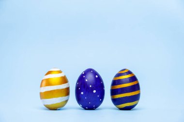 Mavi üzerine çizgili üç Paskalya modası klasik mavi ve altın renkli yumurta deseni. Mesaj için fotokopi alanı olan mutlu Paskalyalar. Asgari biçim