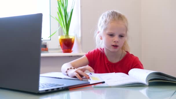Online onderwijs op afstand. Schoolmeisje thuis studeren met digitale tablet en huiswerk maken. Trainingsboeken en notitieboekjes op tafel. — Stockvideo