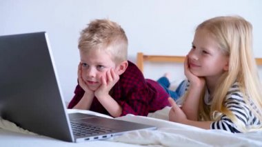 Uzaktan öğrenme çevrimiçi eğitim. Öğrenci çocuk ve kız evde dijital tablet dizüstü bilgisayarla ders çalışıyor ve okul ödevi yapıyor. Eğitim kitaplarıyla yatakta oturmak..