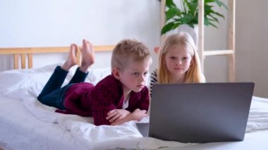 Uzaktan öğrenme çevrimiçi eğitim. Öğrenci çocuk ve kız evde dijital tablet dizüstü bilgisayarla ders çalışıyor ve okul ödevi yapıyor. Eğitim kitaplarıyla yatakta oturmak..