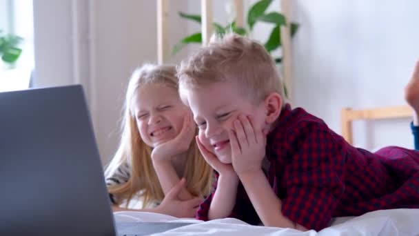 Távolsági tanulás online oktatás. Iskolásfiú és lány otthon tanul digitális táblagéppel, laptoppal és házi feladatot csinál. Ülni az ágyon az oktatókönyvekkel. — Stock videók