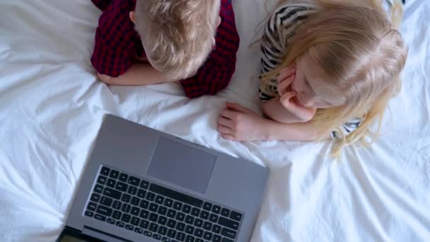 Educação online à distância. vista superior sobre Schoolboy e menina estudando em casa com notebook tablet digital laptop e fazer lição de casa da escola. Sentado na cama 23.03.2020 São Petersburgo Rússia — Vídeo de Stock