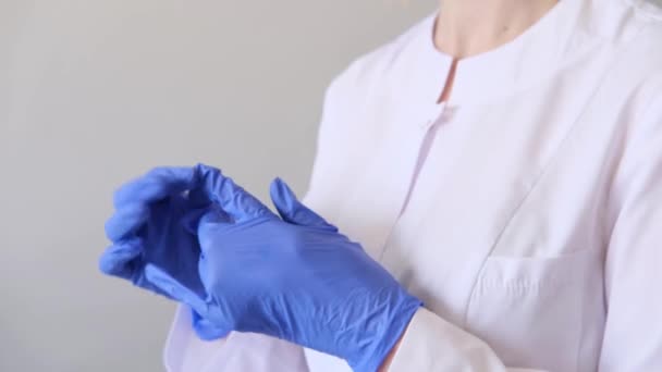 Un medico chirurgo donna in uniforme bianca mette i guanti blu. Concetto di igiene, trattamento, medicina — Video Stock