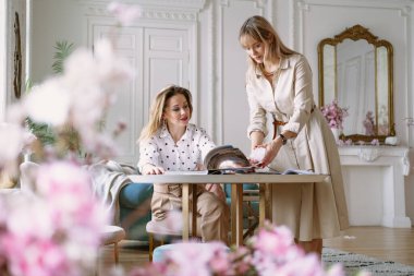 Stüdyoda dizüstü bilgisayarlar, dergiler ve çizimler kullanarak yeni bir proje üzerinde çalışan moda tasarımcıları. Gülümseyen iki genç kadın fikirleri tartışıyor..