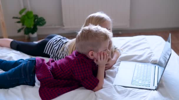 Дистанційне навчання онлайн-освіти. Шкільний хлопець і дівчина навчаються вдома з цифровим ноутбуком для планшетів і роблять шкільні домашні завдання. Сидячи на ліжку з навчальними книгами . — стокове відео