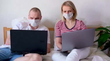 4K genç aile evlerinden uzakta bilgisayarın başında yatıyorlar. Tıbbi maskeli karantina altındaki bir çift koronavirüs. Kendine dikkat et. Mesafe öğrenme, eğitim ve çalışma. İnternetten gıda siparişi