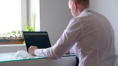 4K maskeli, ofis kıyafetli, beyaz gömlekli ve kravatlı bir adam ev bilgisayarından iş görüşmesi yapıyor. Evde güvende kalma çağrısı. Mesafe çalışması. Karantina