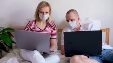 4K genç aile evlerinden uzakta bilgisayarın başında yatıyorlar. Tıbbi maskeli karantina altındaki bir çift koronavirüs. Kendine dikkat et. Mesafe öğrenme, eğitim ve çalışma. İnternetten gıda siparişi