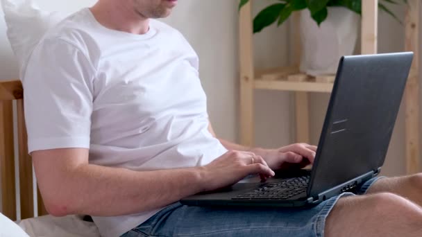 4k Unerkennbarer Mann arbeitet im Büro von zu Hause aus auf dem Bett. Mit dem Computer. Die Aufforderung, sicher zu Hause zu bleiben. Online-Fernstudium und Arbeit. — Stockvideo