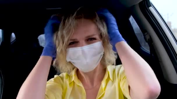 4k Rubia rizada chica conductor en el desgaste de verano y máscara médica y guantes de protección endereza su cabello en el coche antes de conducir. Mujer contra el resfriado gripe común. Quédate en casa en cuarentena . — Vídeos de Stock