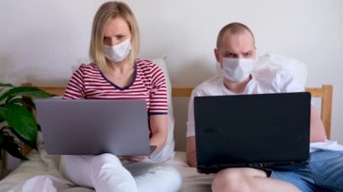 4K genç aile evlerinden uzakta bilgisayarın başında yatıyorlar. Tıbbi maskeli karantina altındaki bir çift koronavirüs. Kendine dikkat et. Mesafe öğrenme, eğitim ve çalışma. İnternetten gıda siparişi