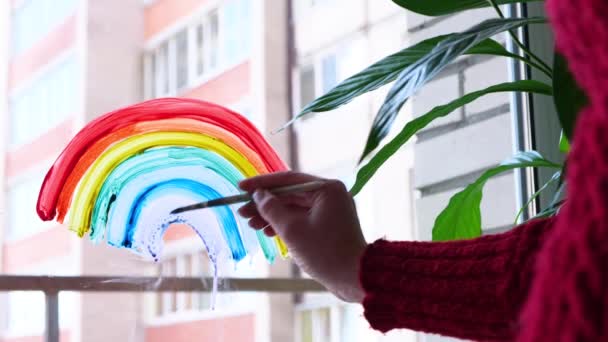 4k. Chica pintando arco iris en la ventana durante la cuarentena Covid-19 en casa. Quédate en casa campaña de medios sociales para la prevención del coronavirus, vamos a estar todos bien, esperanza. Atrapar el arco iris . — Vídeo de stock