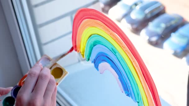 4k. Chica pintando arco iris en la ventana durante la cuarentena Covid-19 en casa. Quédate en casa campaña de medios sociales para la prevención del coronavirus, vamos a estar todos bien, esperanza. Atrapar el arco iris . — Vídeos de Stock