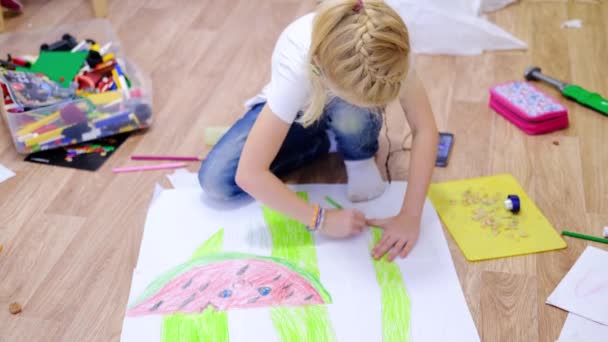 4k. Niños en casa. Cierra las manos de la niña rubia dibujando una foto de verano con sandía en el suelo. Cuarentena. Quédate en casa. — Vídeos de Stock