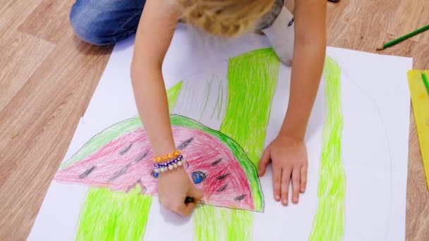 4k. Niños en casa. Cierra las manos de la niña rubia dibujando una foto de verano con sandía en el suelo. Cuarentena. Quédate en casa. — Vídeos de Stock
