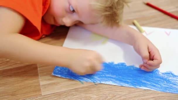 4k. Barn hemma. Närbild händer lilla blonda pojke rita sommarbild med gul sol och blått hav på golvet. Karantän. Stanna hemma — Stockvideo