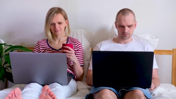 4k junge Familie arbeitet von zu Hause aus am Bett am Computer. Coronavirus unter Quarantäne. Bleiben Sie sicher zu Hause. Fernstudium, Ausbildung und Arbeit. Lebensmittel online bestellen — Stockvideo