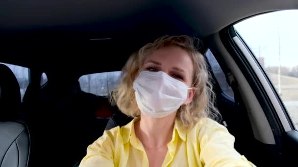 4k Kudrnaté blondýny dívka řidič ve žlutém letním oblečení a lékařské masky a ochranné rukavice tančí v autě před řízením. Žena proti nachlazení běžné chřipky. Zůstaň doma v karanténě. — Stock video