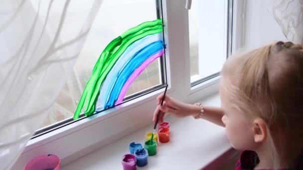 4k. Flicka måla regnbåge på fönster under Covid-19 karantän hemma. Stanna hemma sociala medier kampanj för att förebygga coronavirus, låt allt vara bra, hopp. Jaga regnbågen — Stockvideo