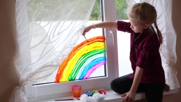 4k. Chica pintando arco iris en la ventana durante la cuarentena Covid-19 en casa. Quédate en casa campaña de medios sociales para la prevención del coronavirus, vamos a estar todos bien, esperanza. Perseguir el arco iris — Vídeos de Stock