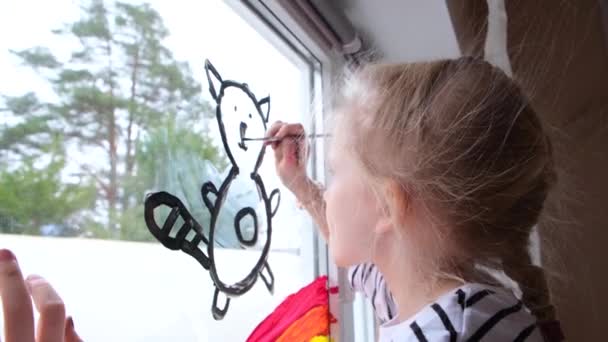 4k. Chica pintando arco iris y gato en la ventana durante la cuarentena Covid-19 en casa. Quédate en casa. Idea de casa de niños. Perseguir el arco iris — Vídeo de stock