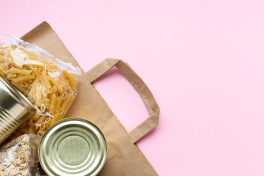 Pembe karantina süresi için yiyecek stokları ile dolu kağıt torba. Pirinç, makarna, yulaf ezmesi, konserve yiyecek, şeker, tuvalet kağıdı. Yemek teslimatı, bağış, koronavirüs. Kopyalama alanı