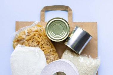 Mavi karantina dönemi için yiyecek stoğu içeren kağıt torba. Pirinç, makarna, yulaf ezmesi, konserve yiyecek, şeker, tuvalet kağıdı. Yemek teslimatı, bağış, koronavirüs.