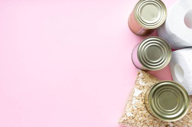 Pembe arka planda karantina süresi için yiyecek stoku. Pirinç, makarna, yulaf ezmesi, konserve yiyecek, şeker, tuvalet kağıdı. Yemek teslimatı, bağış, koronavirüs karantinası. Kopyalama alanı