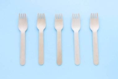 Çevre dostu tek kullanımlık mutfak gereçleri mavi arka planda. Tahta çatallar ve kaşıklar. Ekoloji, sıfır atık kavramı. Üst Manzara. düz yat