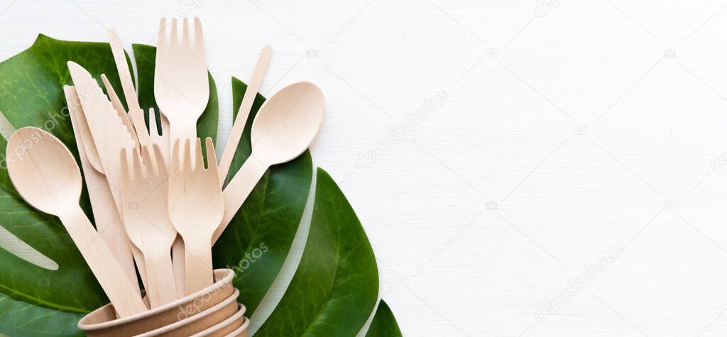 banner eco friendly disposable kitchenware utensils on white background. wooden forks and spoons in paper cup. ecology, zero waste concept. copyspace
