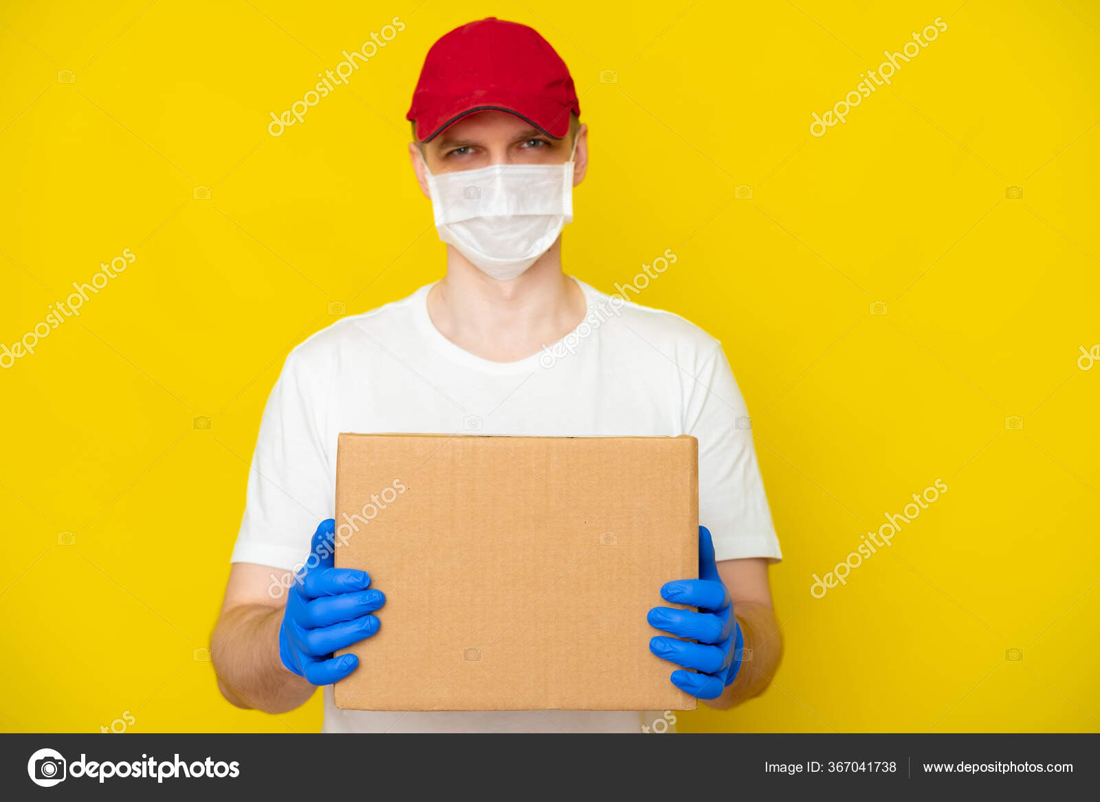 Delivery Man in Yellow Uniform Medical Face Mask and Gloves Holds