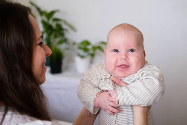 Feliz bebé. Poco más lindo gordito caucásico bebé blanco mirando y sonriendo a la cámara en las manos de la madre. La vida familiar, el amor de las madres, la maternidad — Foto de Stock