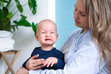 Anne ağlayan huysuz çocuğa sarılıyor. Anne eli üstünde küçük bir bebek. Aile hayatı, annelik.