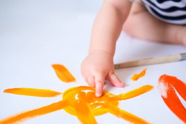 Kırpılmış bebek yerde sürünerek boyayla oynar, parmak sarısı boyalı güneşi yakından gösterir. İyi eğlenceler ve evde oynayın. Yaz