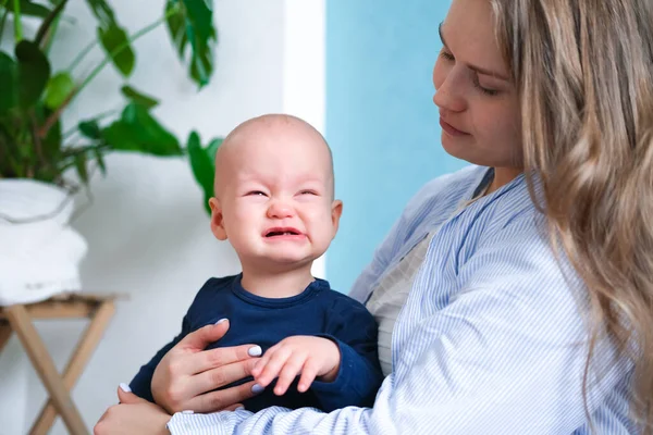 Mamá se abraza llorando rabieta de niño malhumorado. Pequeño bebé en manos de madre. Vida familiar, maternidad — Foto de Stock