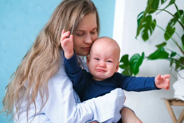 Mamá se abraza llorando rabieta de niño malhumorado. Pequeño bebé en manos de madre. Vida familiar, maternidad — Foto de Stock