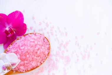 Spa kozmetik ve güzellik tedavi konsepti. Beyaz ahşap arka planda pembe spa deniz tuzu ve mor orkide. çoğaltma düzlemi