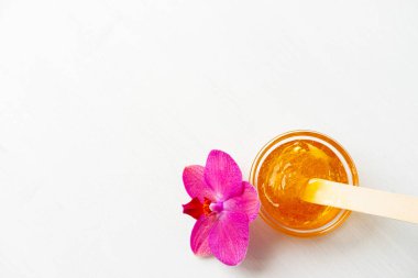 Tahta spatula çubuklarıyla saç kesimi için ballı ya da şekerli bal. çiçek arkaplanı - tüy dökücü ve güzellik konsepti. kopyala
