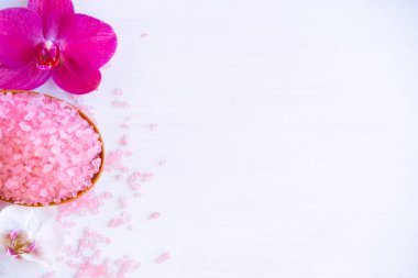 Spa kozmetik ve güzellik tedavi konsepti. Beyaz ahşap arka planda pembe spa deniz tuzu ve mor orkide. çoğaltma düzlemi
