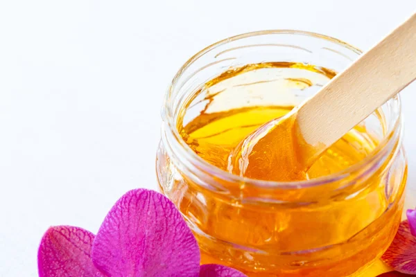 Pasta de azúcar o miel de cera para la depilación con espátula de cera de madera en frasco. fondo de flores - depilación y concepto de belleza —  Fotos de Stock