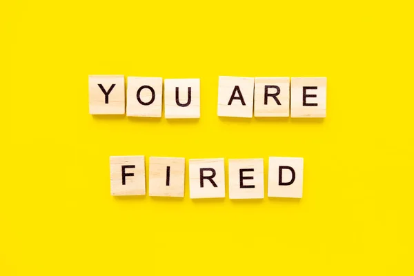 words You Are Fired. Wooden blocks with lettering on top of yellow background. Human Resource Management and Recruitment and Hiring concept