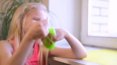 Yanlara yeşil balçık geren bir kız. Çocuk elleri sümük oyuncağı oynuyor. Beyazdan balçık yapmak. Modaya uygun sıvı oyuncak ellere ve parmaklara yapışıyor. 4k görüntü