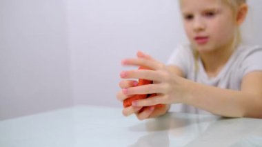 Sarışın kız yanlarına pembe parlak balçık serpiştiriyor. Çocuk elleri sümük oyuncağı oynuyor. Sümük yapıyorum. Kopyalama. Seçici odak.