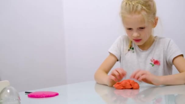 Blondes Mädchen, das rosa Glitzerschleim an die Seiten streckt. Kinderhände spielen Schleimspielzeug. Schleim machen. Kopierraum. Selektiver Fokus. — Stockvideo