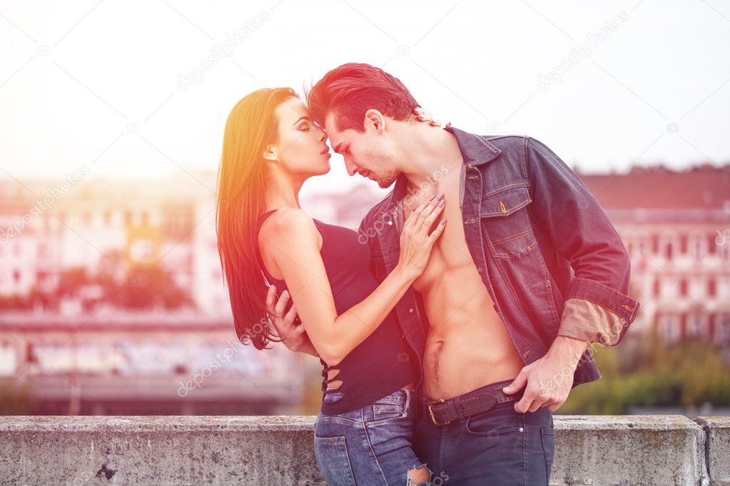 Sexy macho man holding brunette lover in sunset