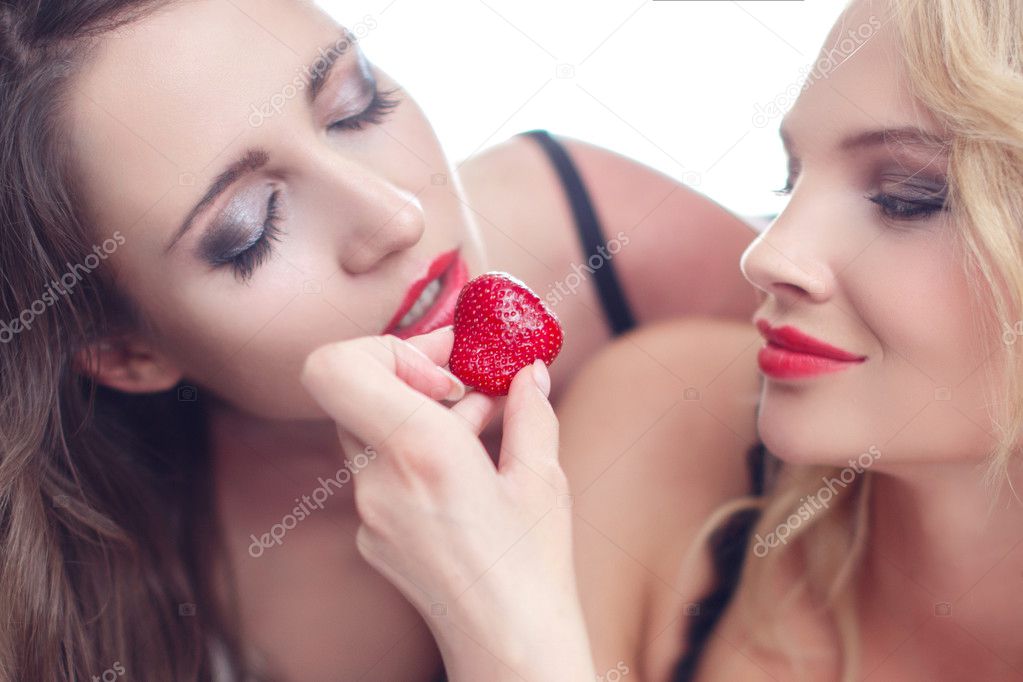 Sexy woman feeding lesbian lover with strawberry
