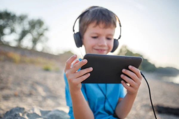 Little boy listening music on tablet outdoor — Stock Photo, Image