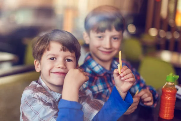 Little boys eating french fries in fast food restaurant — Stock Photo, Image
