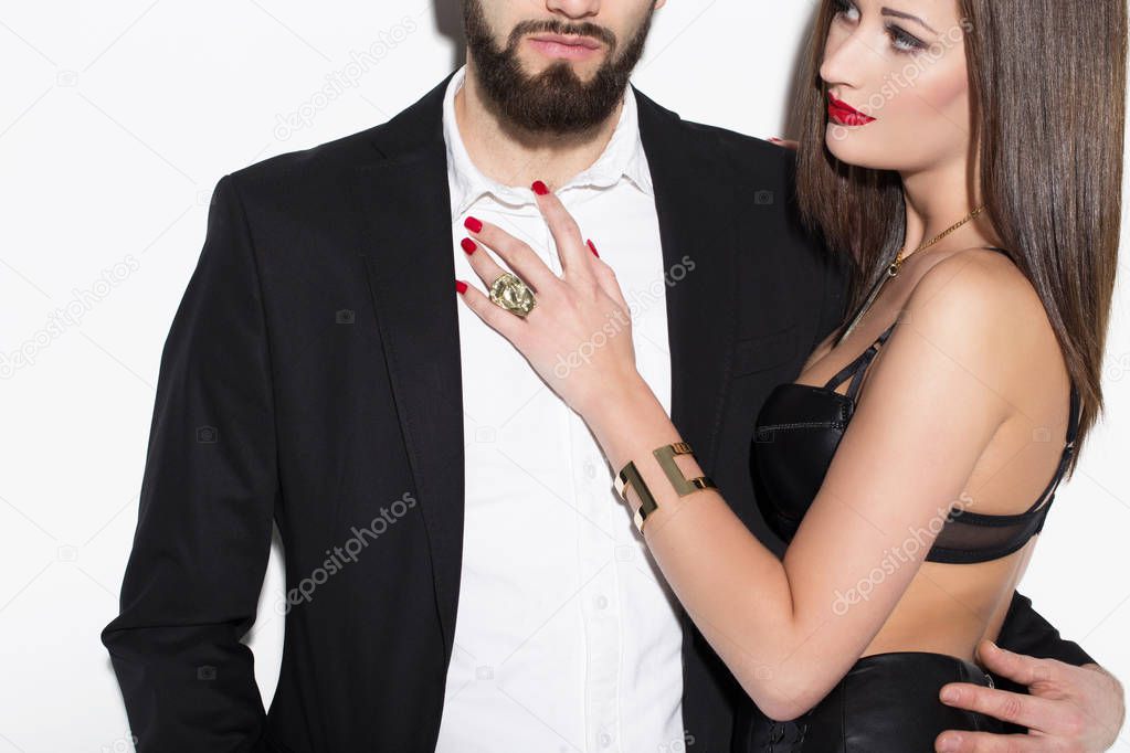 Sexy rich couple posing at white wall closeup